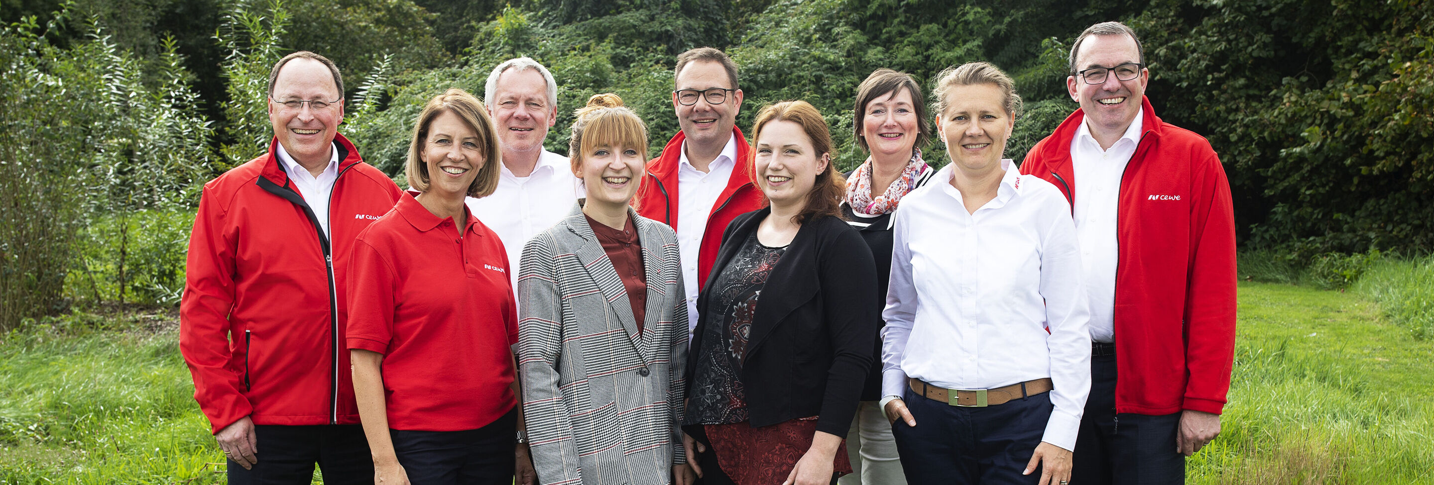 Grupo de personas al aire libre sonriendo, vestidas de rojo y blanco