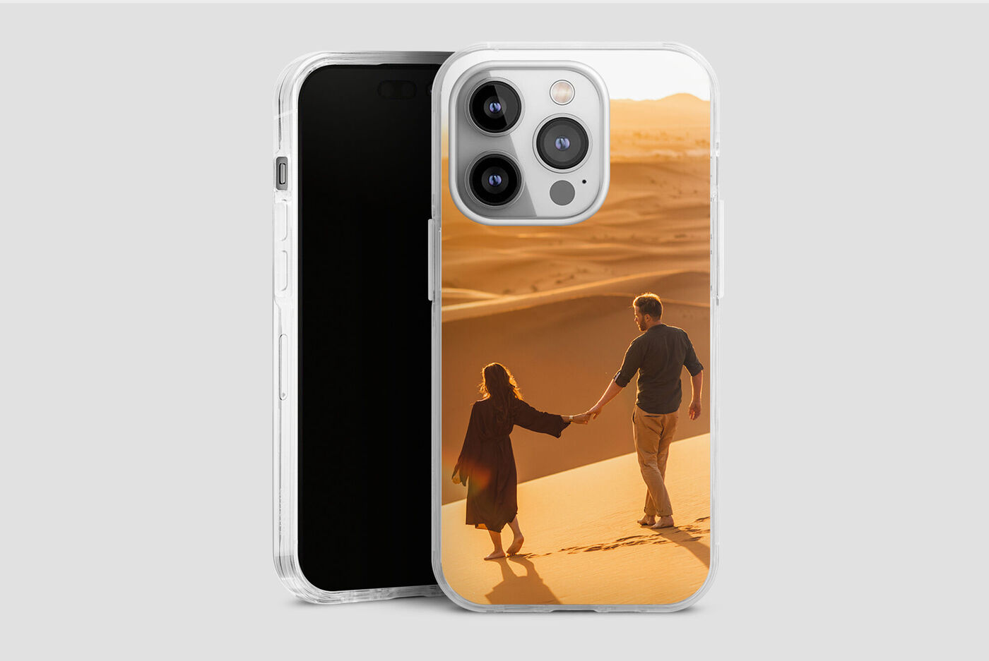 Pareja se toma de la mano mientras caminan por una duna dorada en un cálido atardecer.