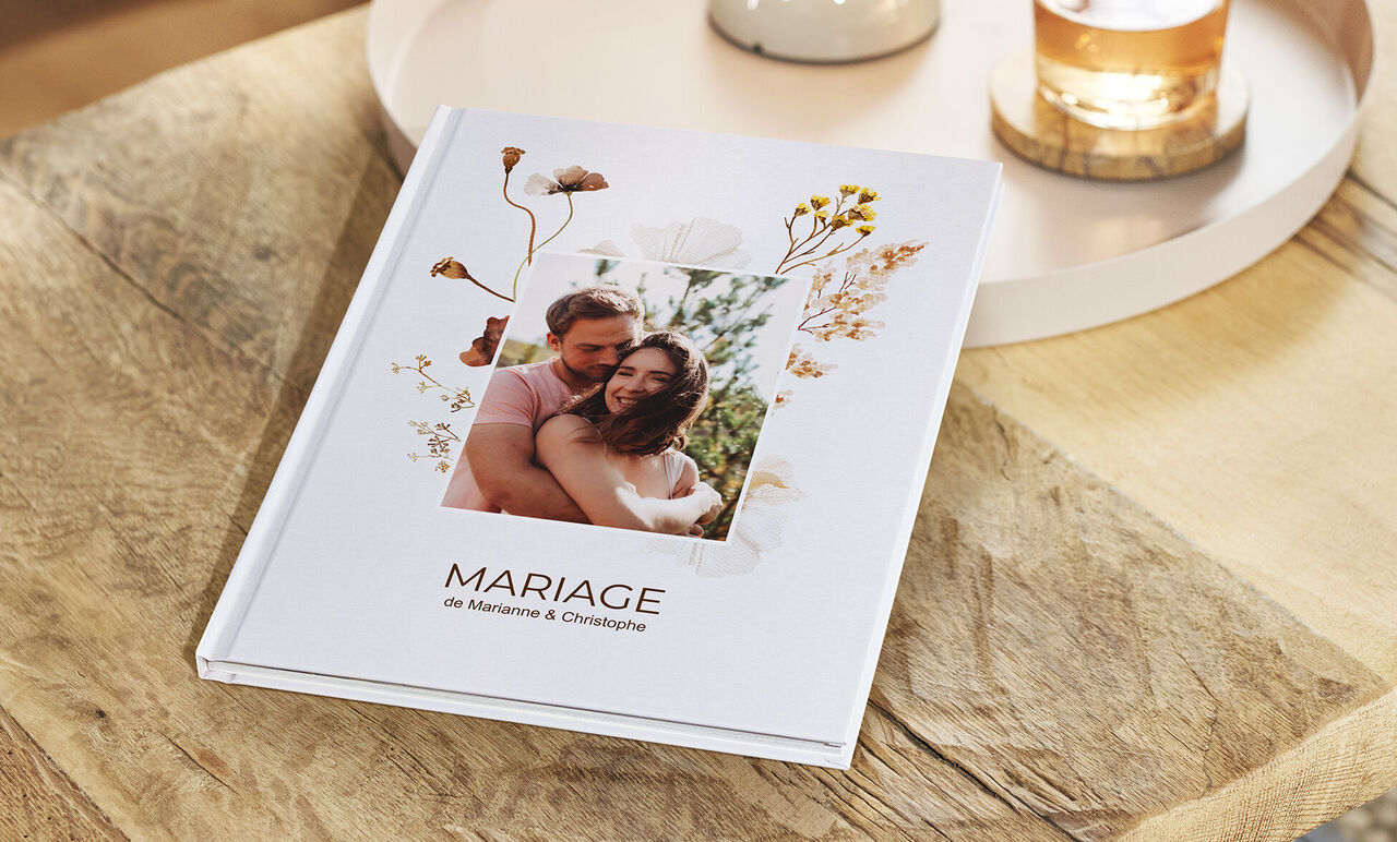 Un elegante libro de fotos CEWE con un diseño floral y una fotografía de boda personal.