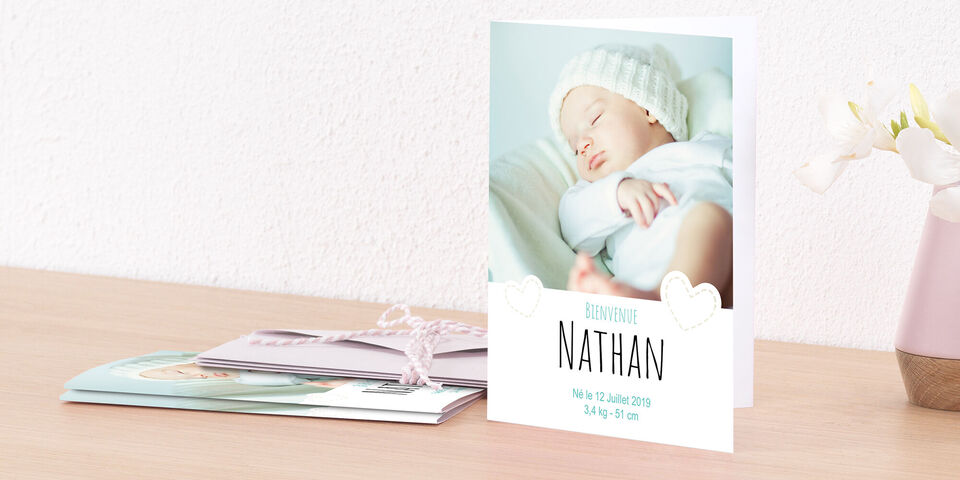 Diseño de tarjeta de nacimiento para Nathan, colocado sobre una mesa.