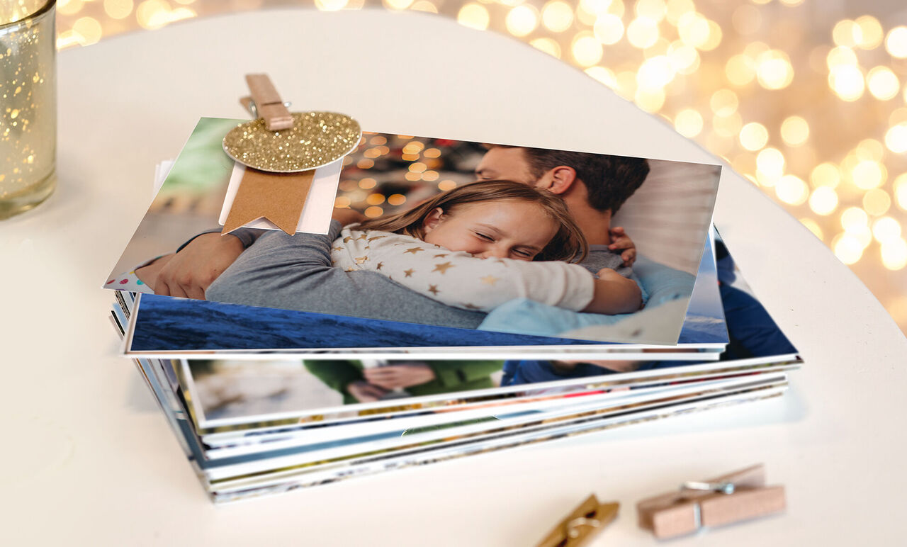 Una mamá abraza a su hijo. Hay muchas fotos en una mesa. Decoraciones brillantes al fondo.