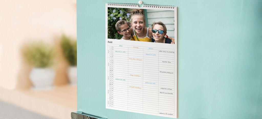 Un calendario CEWE cuelga del frigorífico, con una imagen y un calendario mensual.