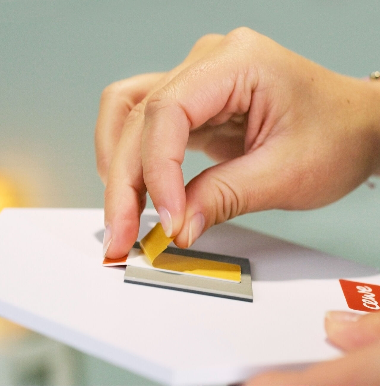 Una mano pega un papel amarillo en una tarjeta de felicitación