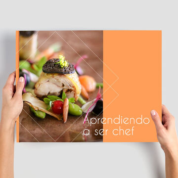 Una persona sostiene un CEWE Fotobuch con platos presentados de forma profesional.