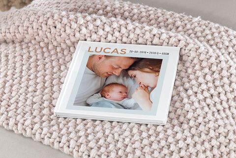 Un CEWE Fotolibro sobre una manta acogedora, con imágenes de una familia.