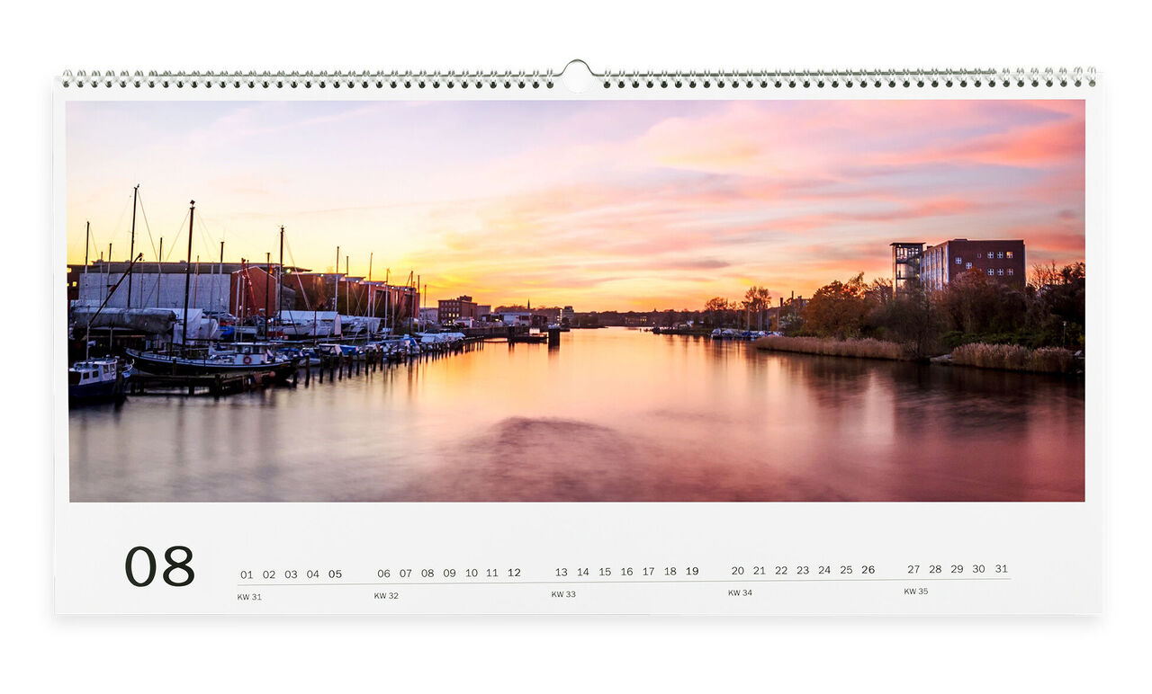 Un hermoso atardecer sobre un río tranquilo con botes, representado en el calendario de fotos CEWE.