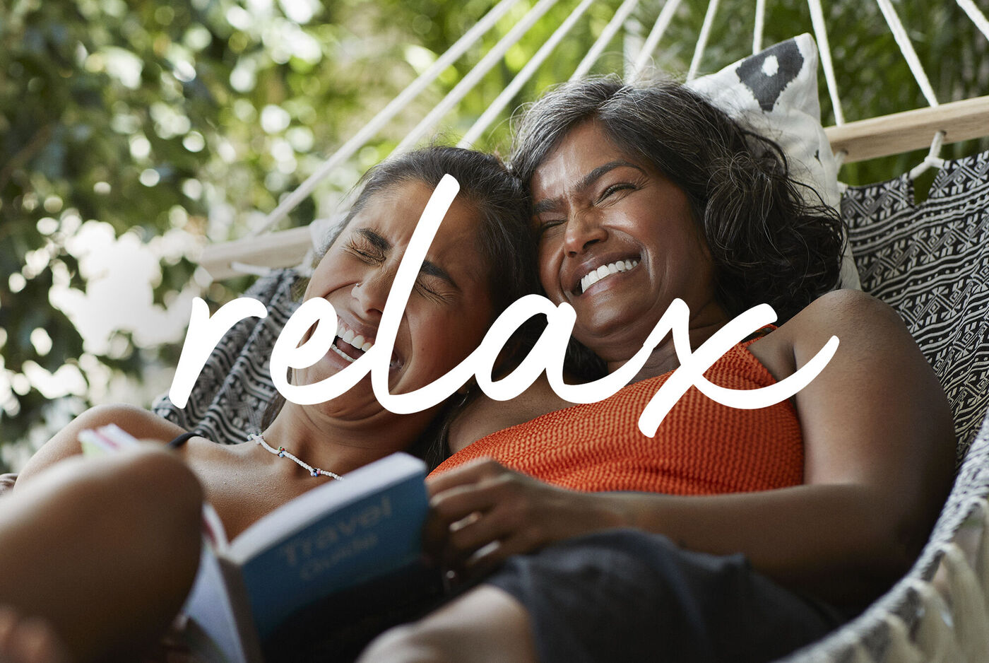 Dos mujeres disfrutan de su tiempo en una hamaca y leen.