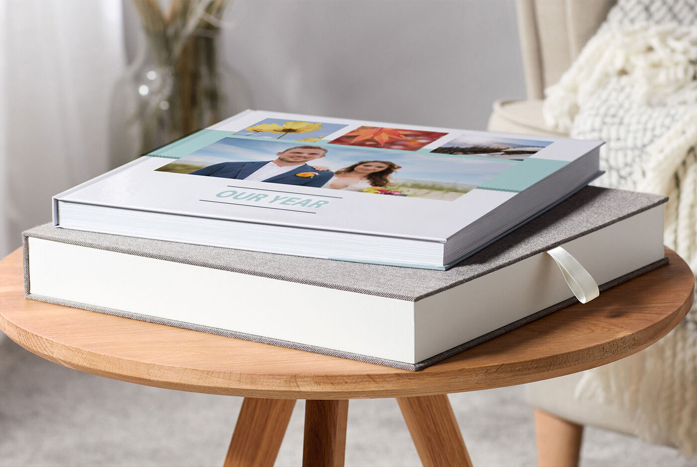 Dos CEWE FOTOBÚCHER sobre una mesa. Un libro tiene una tapa con fotos, el otro es sencillo y decorativo.
