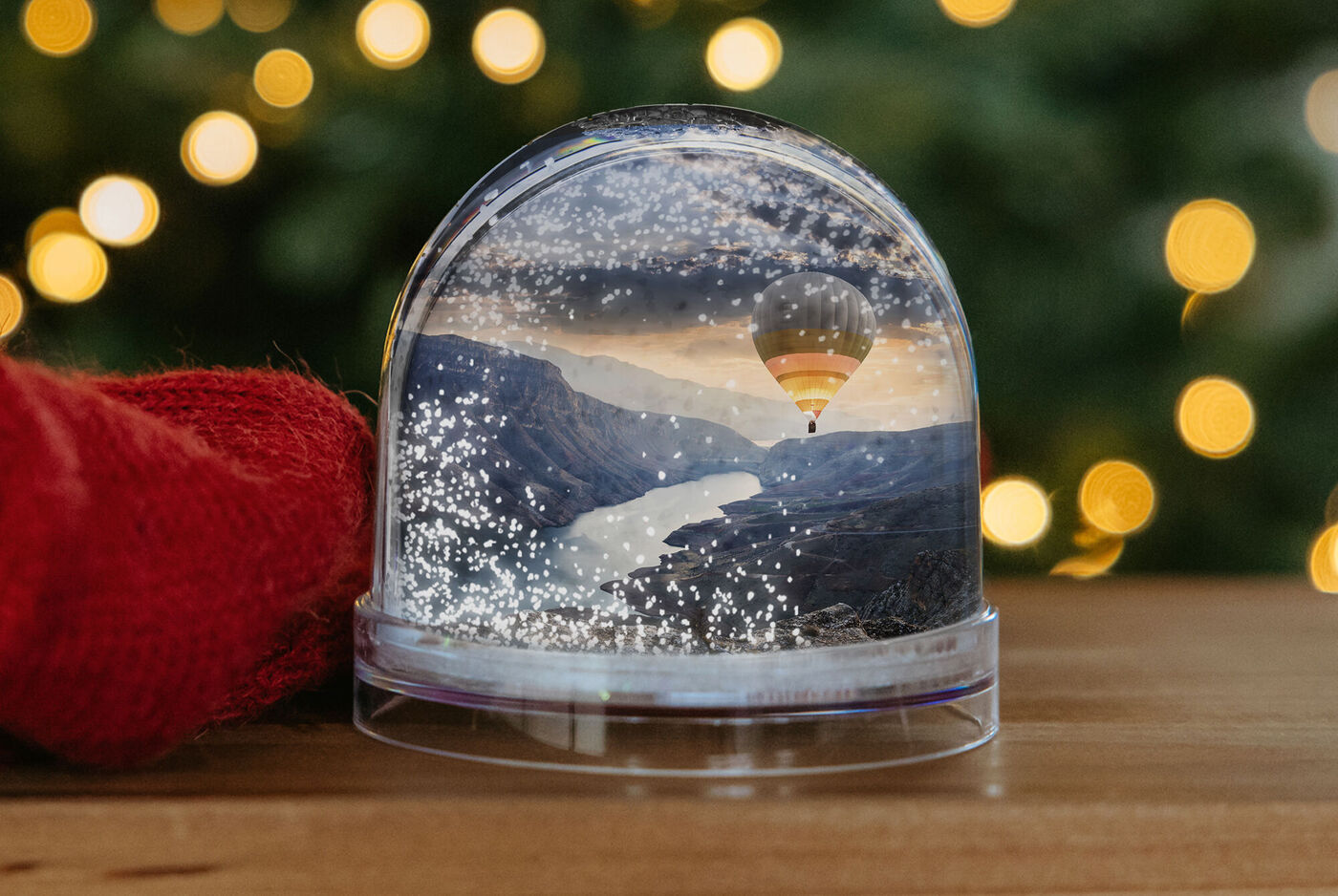 Bola de nieve con paisaje montañoso y globo aerostático sobre fondos brillantes