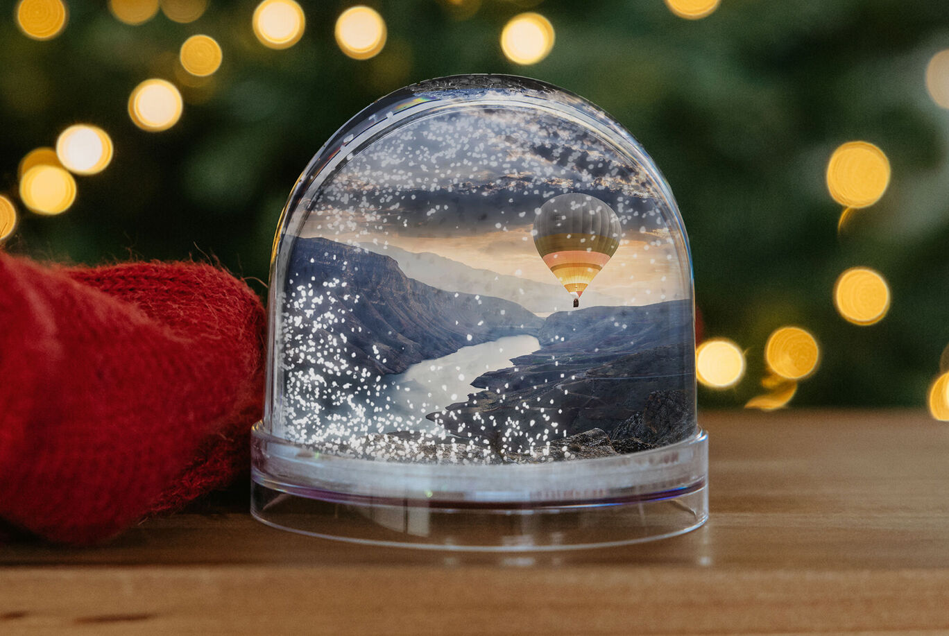 Bola de nieve con paisaje montañoso y globo aerostático sobre fondos brillantes