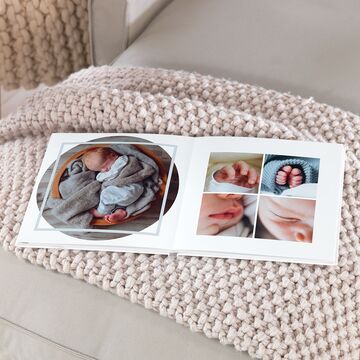 Un álbum CEWE con fotografías de bebé sobre una manta suave.