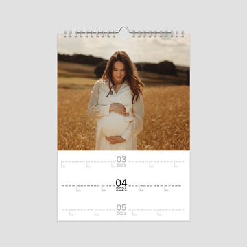 Mujer embarazada en un campo dorado de trigo, sonriente y tocando su vientre