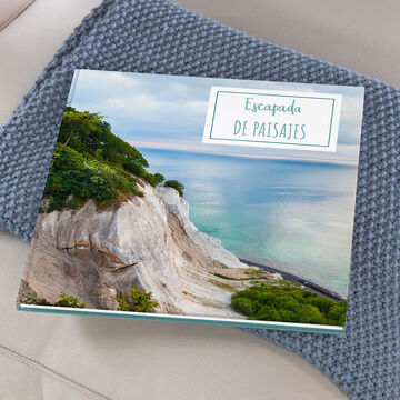 Un hermoso libro fotográfico con un paisaje costero en la portada sobre una manta suave.