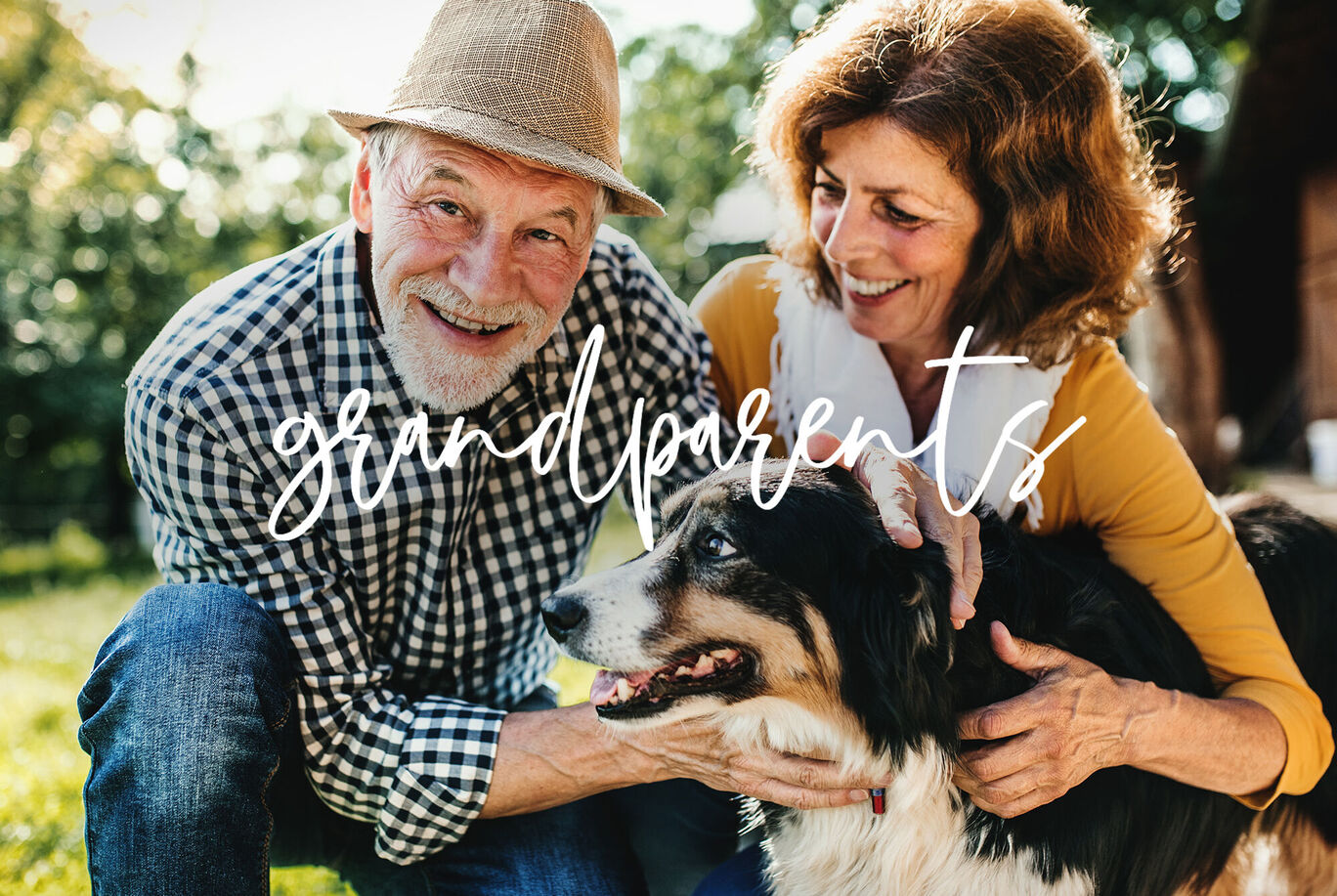 Una pareja mayor se arrodilla en un césped acariciando a un perro.