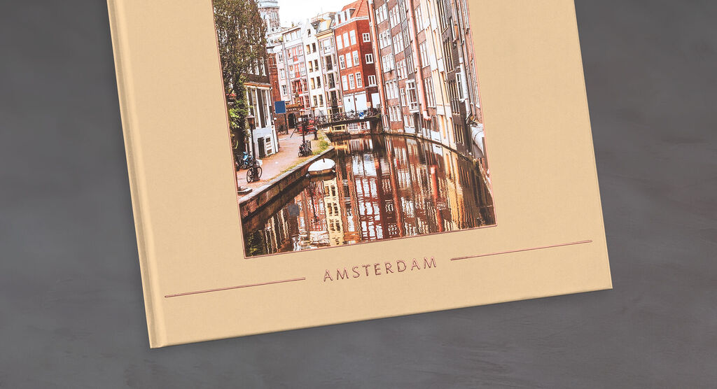 Un libro de fotos CEWE con una imagen de calles y canales grises de Ámsterdam.