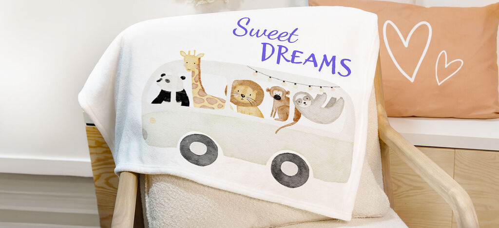 Una suave manta infantil blanca con un diseño colorido de animales que muestra un auto con animales y la frase "Sweet Dreams".