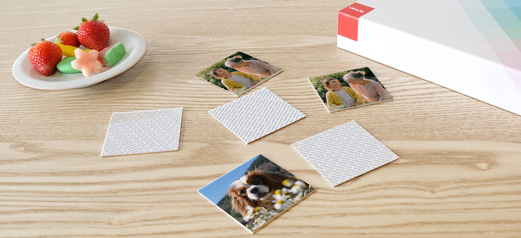 Cinco fotos pequeñas junto a un plato con fruta y dulces sobre una mesa de madera.