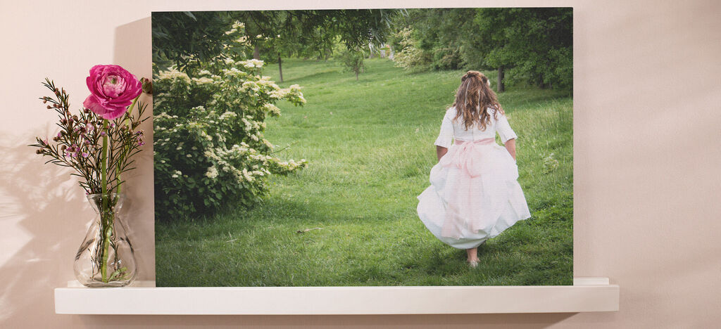 Una niña con chaqueta de primavera corre descalza sobre un campo verde. Lleva un vestido blanco con una falda de tul rosa.