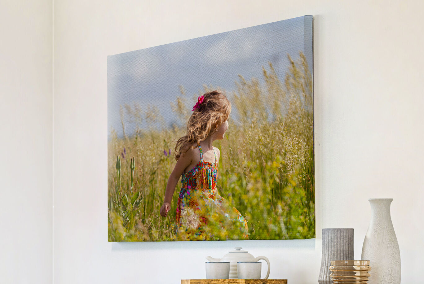 Una niña feliz con rizos rubios en un vestido colorido corre por un campo en flor.