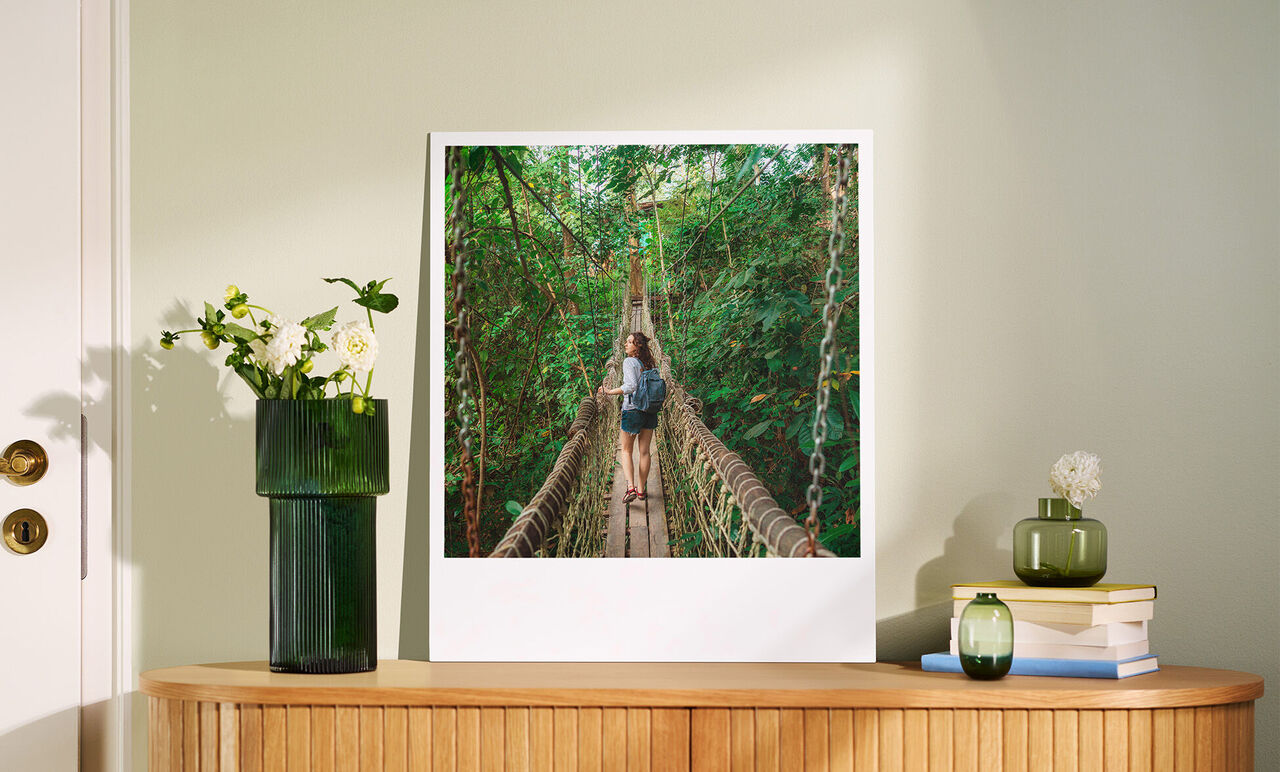 Dos personas disfrutan de un paseo por un puente colgante en un bosque verde.