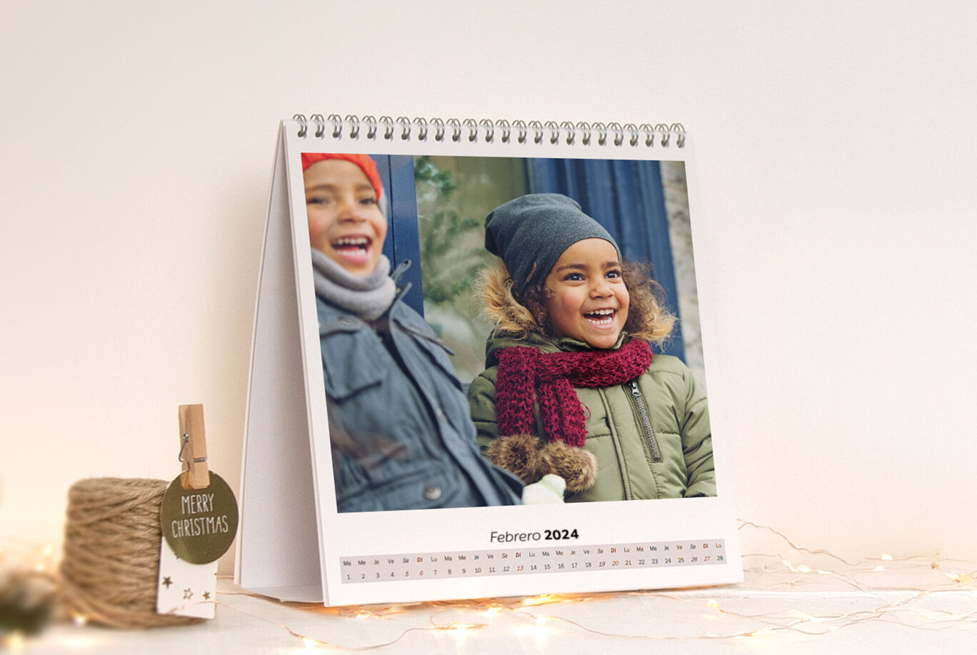 Un calendario de mesa para febrero de 2024 con un bonito motivo invernal y un colgante que dice 'Feliz Navidad'.