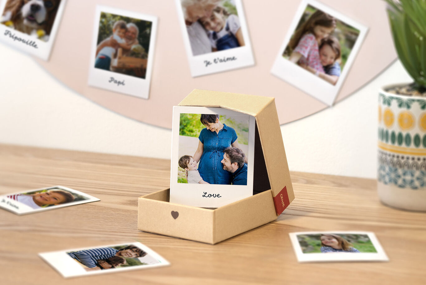 Un hermoso conjunto de regalo en una caja, con una foto de una mujer embarazada y un hombre mirándose con amor. Más fotos de recuerdos personales alrededor.