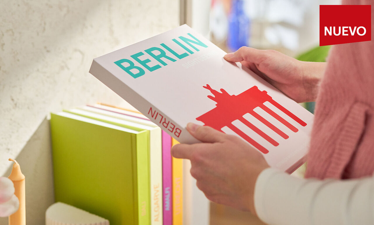 Persona sacando un álbum de fotos “Berlin” de la Colección Mundo de una estantería.