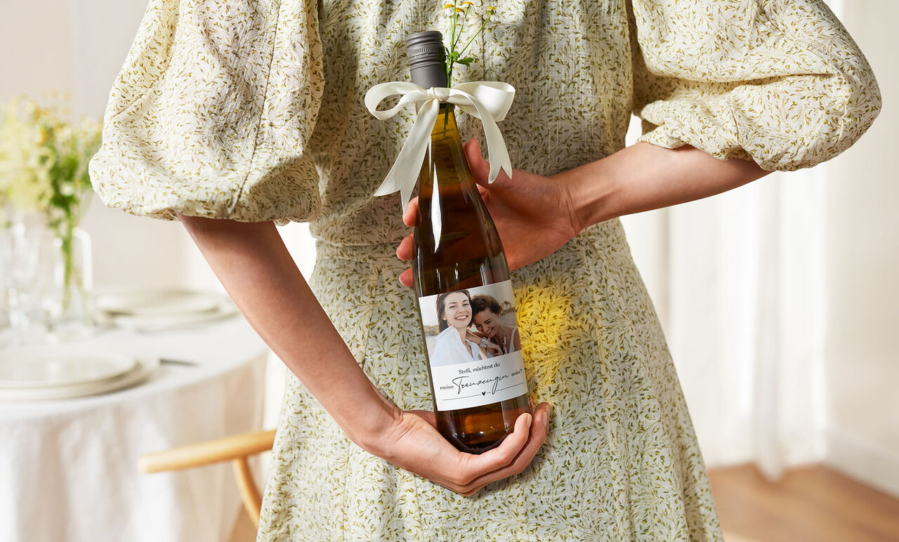 Botella de vino con una etiqueta con foto personalizada en manos de una persona. Perfecta para hacer un regalo.