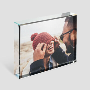 Una pareja disfruta de un momento cálido en la playa. El hombre le coloca un gorro a la mujer.