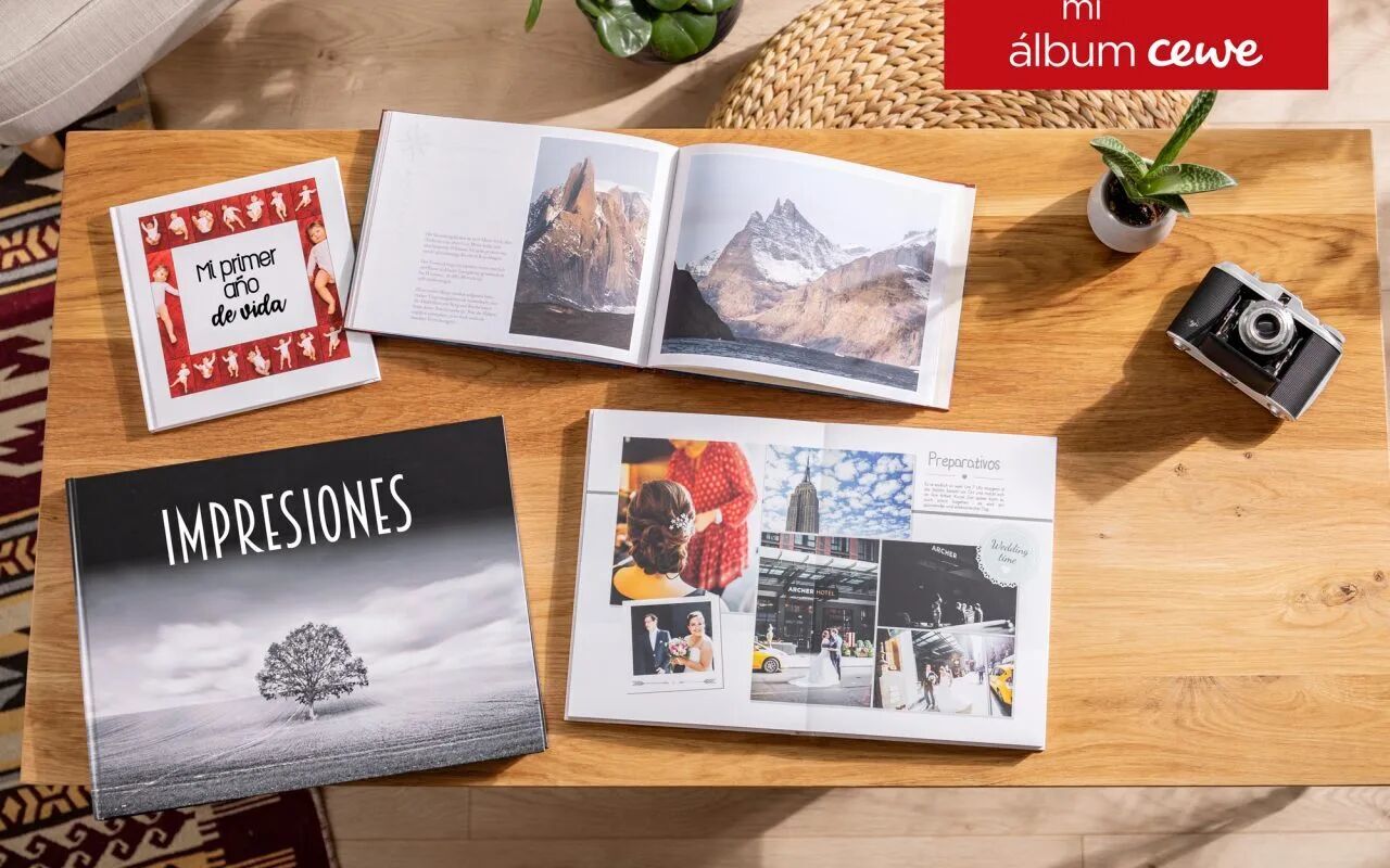 Varios álbumes de fotos y un calendario sobre una mesa de madera con fotos y una cámara.