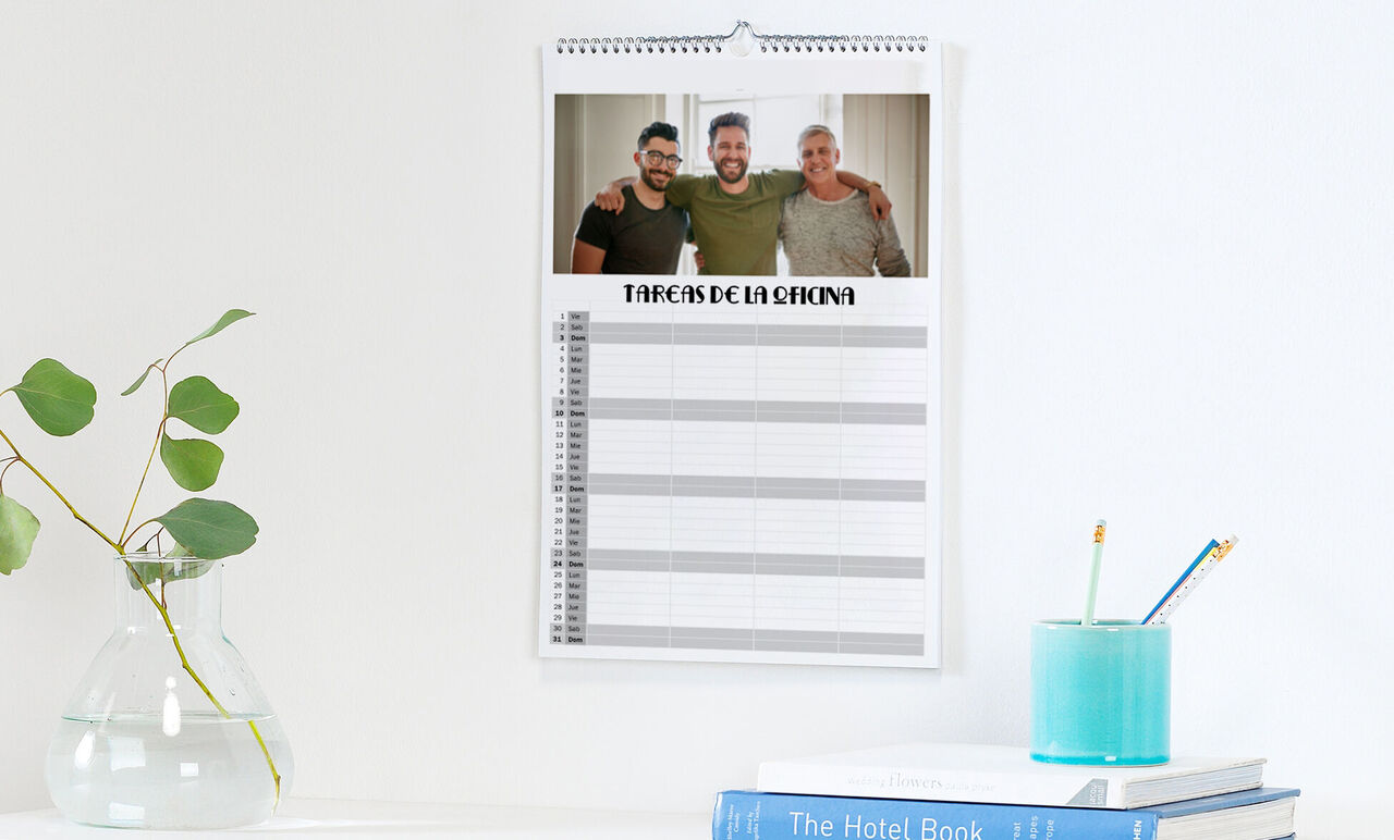 Un calendario fotográfico colgado en la pared con la imagen de tres hombres felices riendo juntos.