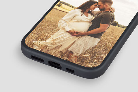 Mujer embarazada y hombre se abrazan en un campo dorado.