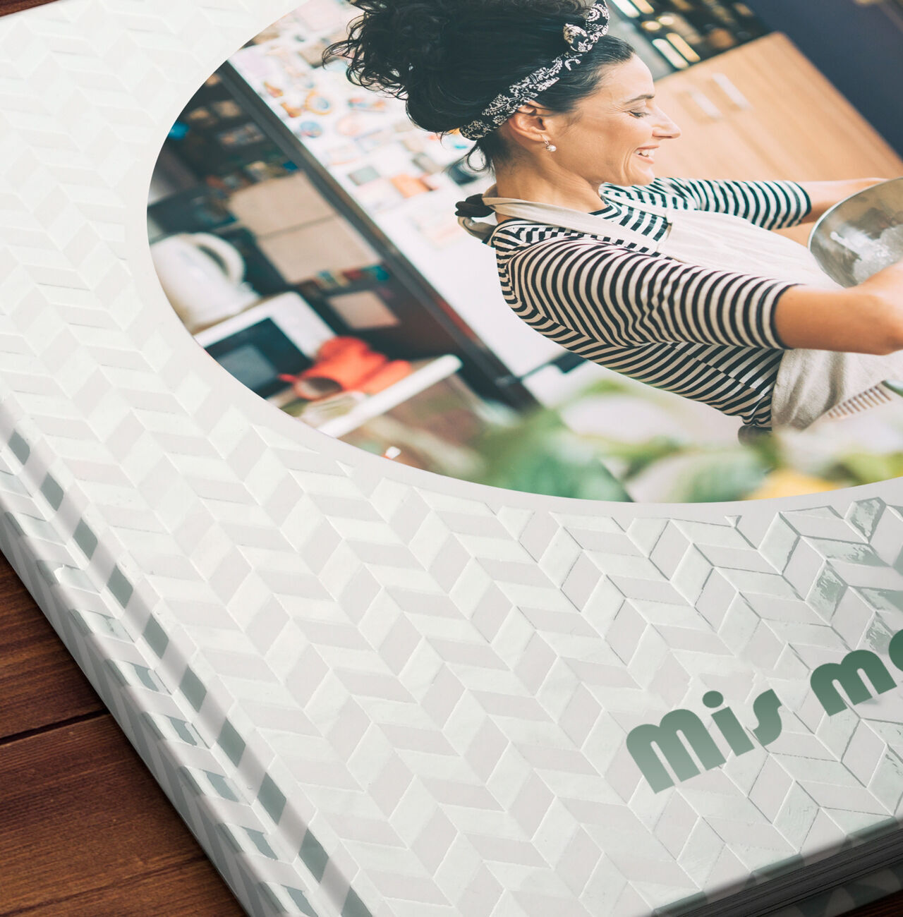 Un CEWE Fotobuch con un diseño creativo y una persona cocinando en una cocina moderna.