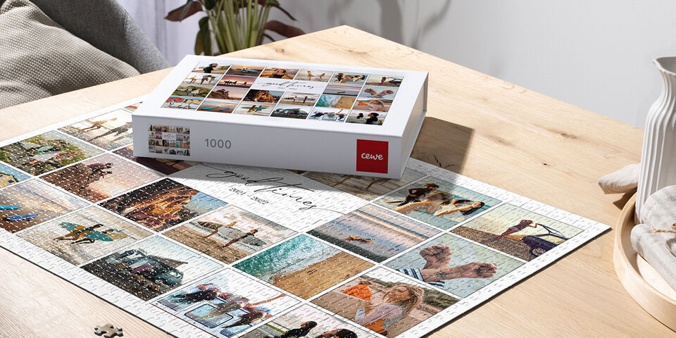 Un fotolibro CEWE está sobre una mesa de madera clara, rodeado de tarjetas de fotos de momentos de vacaciones bien organizadas.