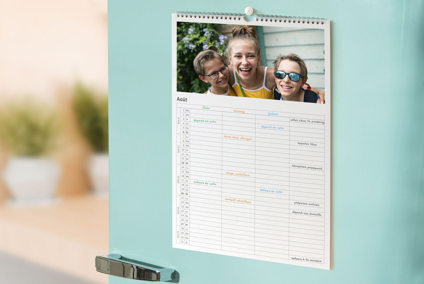 Un calendario en el frigorífico, con un diseño colorido y una imagen alegre de tres amigos al fondo.