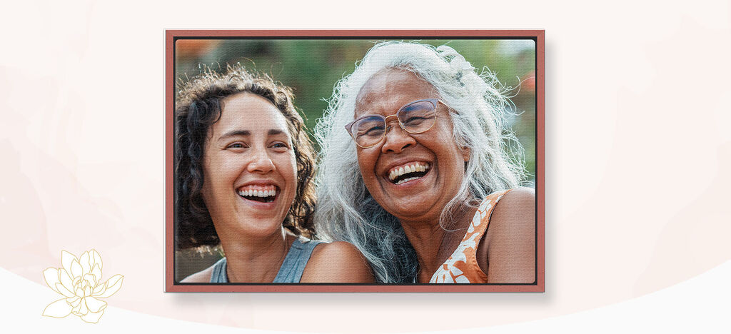 Dos mujeres con caras felices y largas cabelleras, riendo juntas en ropa de verano.