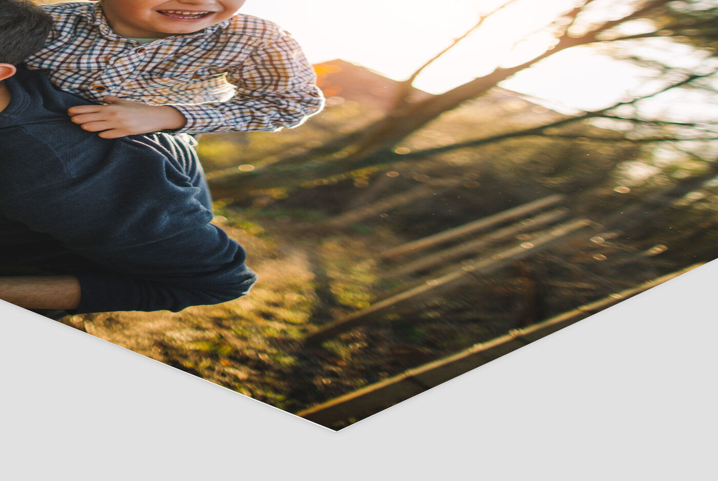 Un padre lleva a su hijo sonriente sobre los hombros al atardecer en la naturaleza.