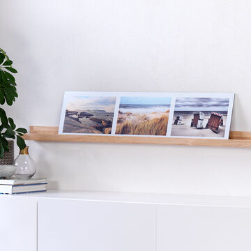 Tres fotos en una estantería moderna junto a una planta.