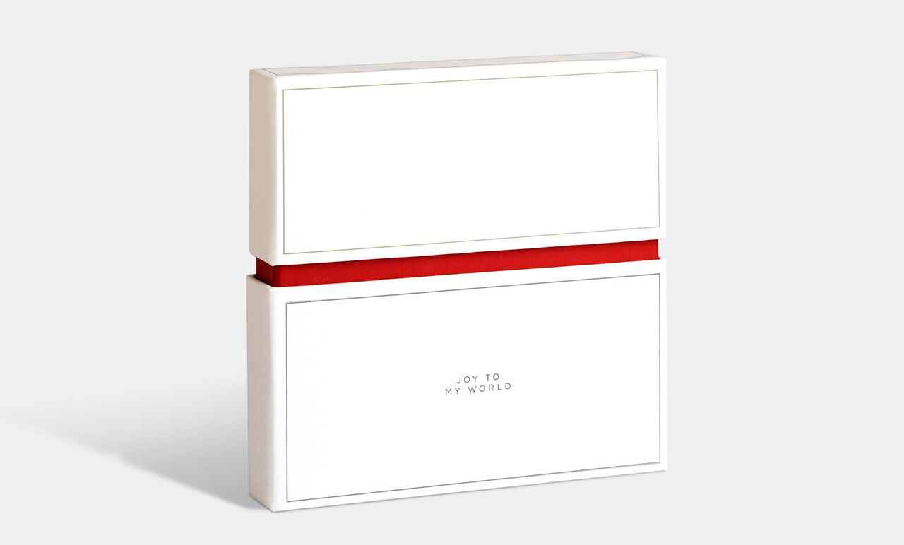 Embalaje de regalo en blanco con cinta roja, etiquetado con 'Joy to my world'