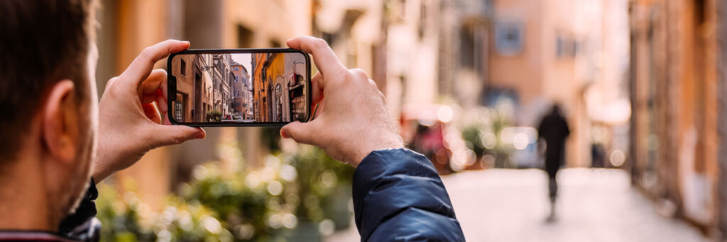 Hombre fotografiando una calle pintoresca con su smartphone para editar sus fotos después.