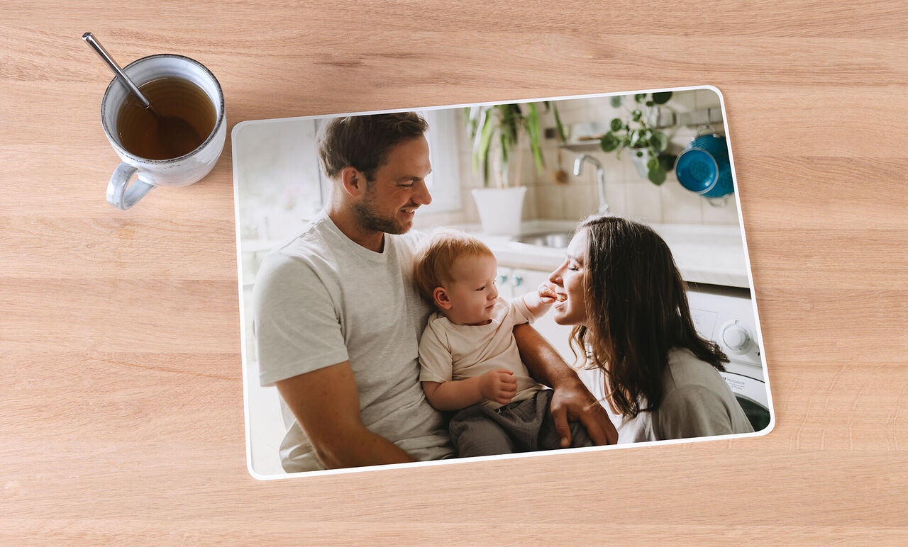 Una familia está sentada en la mesa de la cocina, el padre sostiene al bebé mientras la madre sonríe