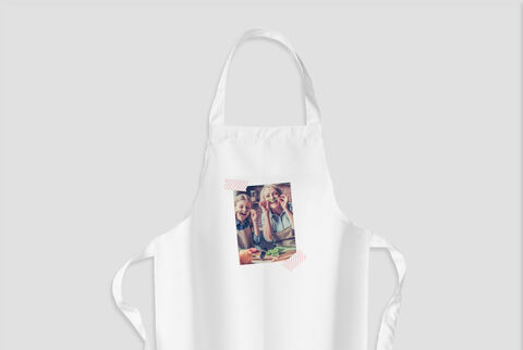 La imagen muestra dos niños sonrientes en delantales cocinando juntos en la cocina y divirtiéndose.