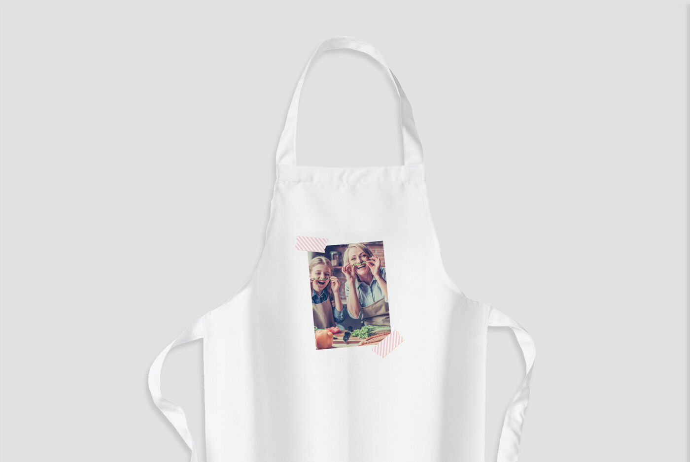 La imagen muestra dos niños sonrientes en delantal personalizado cocinando juntos en la cocina y divirtiéndose.