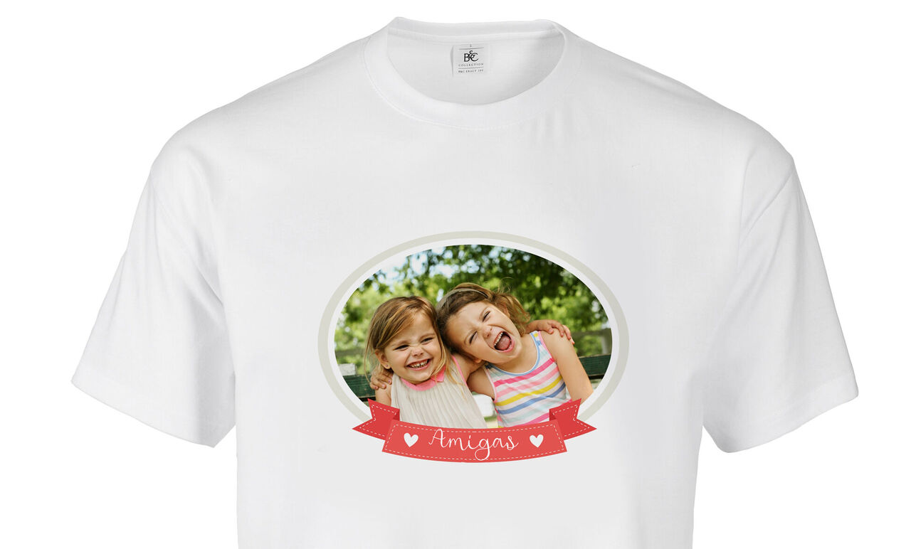 Dos amigas sonríen felices en una camiseta frente a un fondo verde.