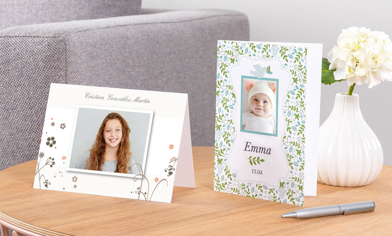 Dos tarjetas de felicitación personalizadas y elegantes sobre una mesa, una floral y otra con foto.